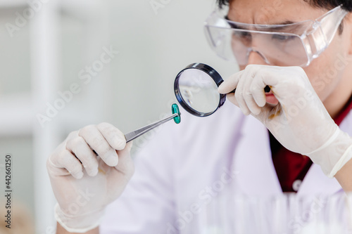 Medicine production quality assurance and care concept. Scientist in medical factory using magnifying glass to checking defective medical pill products. photo