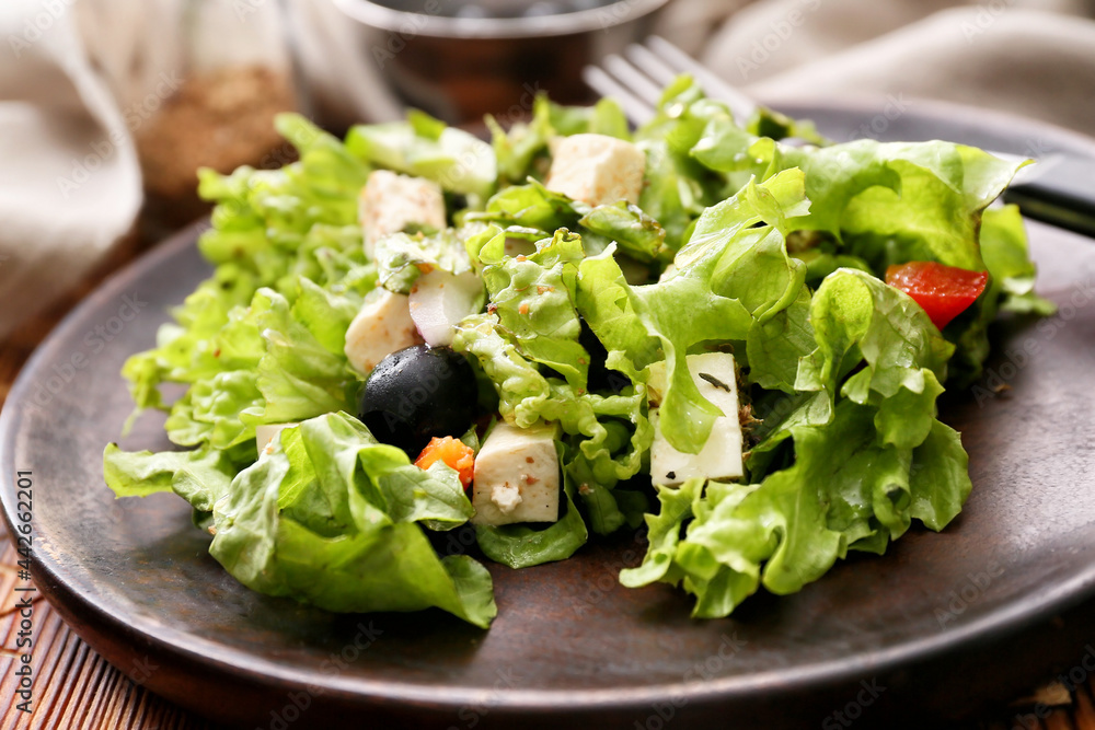 Wooden plate with fresh Greek salad on wooden background, closeup Wooden plate with fresh Greek salad on wooden background, closeup
