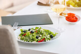 Plate with fresh Greek salad and glass of wine on table in restaurant