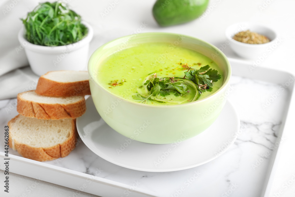 Tray with green gazpacho and ingredients on light background Tray with green gazpacho and ingredients on light background