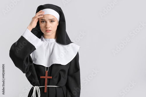 Young sad nun on light back...