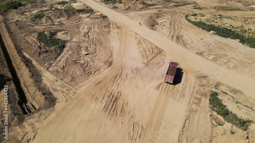 Dump truck transported sand from the open pit. Truck with tipper semi trailer working in quarry. Arial view of the opencast mine. Sand and gravel is excavated from ground. Mining industry. photo