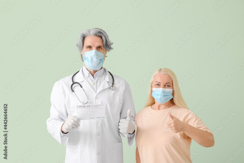 Doctor and patient with International Certificate of Vaccination showing thumb-up on color background Doctor and patient with International Certificate of Vaccination showing thumb-up on color background