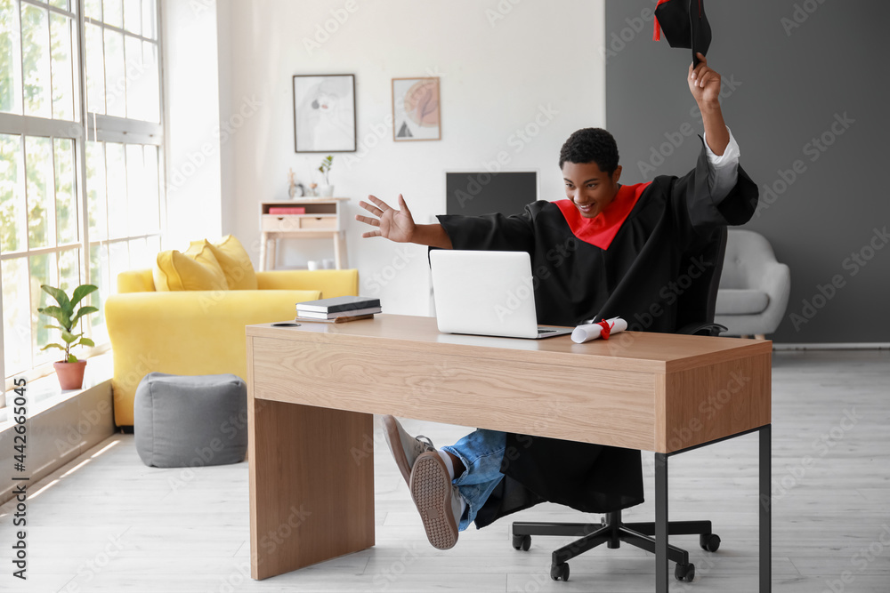 Happy African-American student on his graduation day at home. Concept of online education Happy African-American student on his graduation day at home. Concept of online education