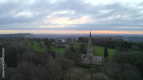 An aerial shot flying past an old English church on a hill in Ranmore common, in Dorking at sunrise photo