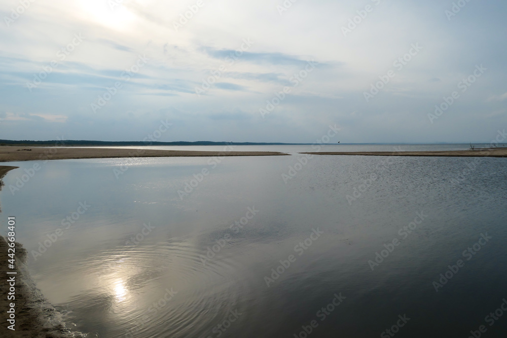 The coastal line of a sandy beach by the Baltic Sea on Sobieszewo island, Poland. The sea is gently waving. A bit of overcast. Solitude and serenity The coastal line of a sandy beach by the Baltic Sea on Sobieszewo island, Poland. The sea is gently waving. A bit of overcast. Solitude and serenity