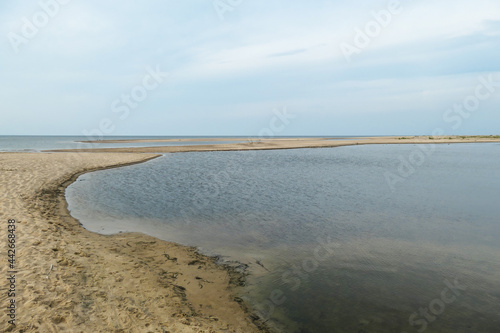 The coastal line of a sandy beach by the Baltic Sea on Sobieszewo island  Poland. The sea is gently waving. A bit of overcast. Solitude and serenity