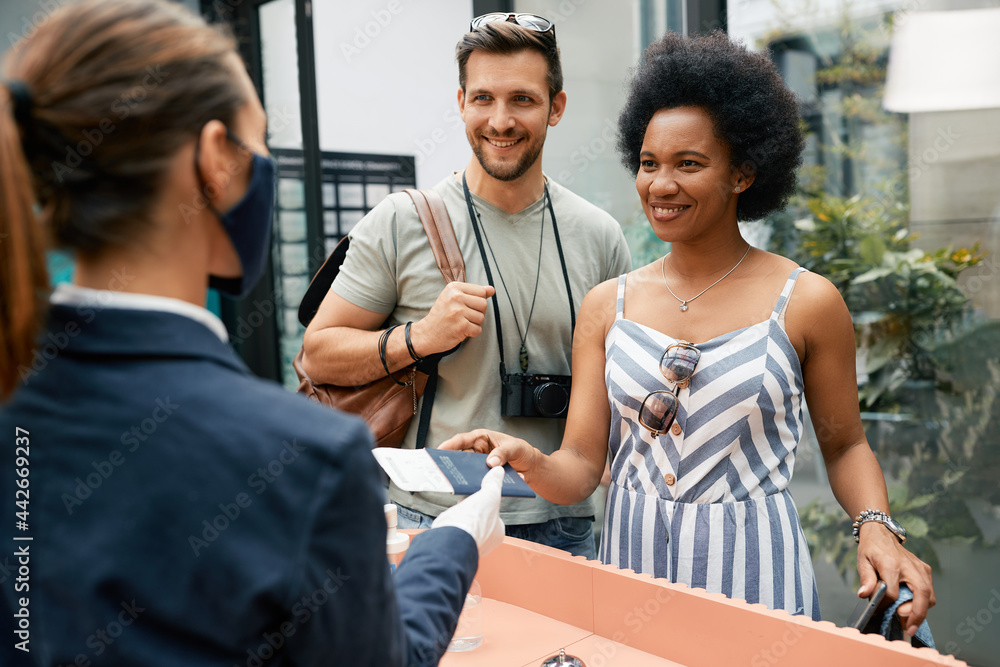Happy black woman and her husband giving passport to receptions during check-in at a hotel. Happy black woman and her husband giving passport to receptions during check-in at a hotel.