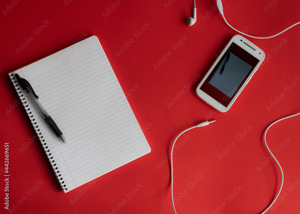 Fototapeta premium Top view desk. Red Background office desk table with notepad and smartphone