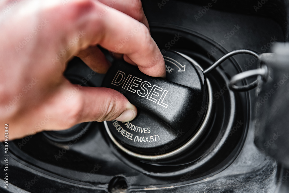 Hand opens fuel cap of black car to fill it with fuel. Stock Photo