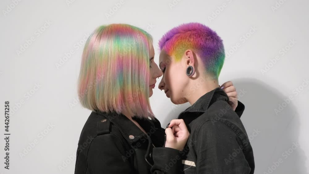 Young lesbian woman couple with vivd colored short hair and jackets posing on white background. Piercing on the face, tunnels in the ears. The concept of same-sex wedding. Stock ビデオ | Adobe Stock