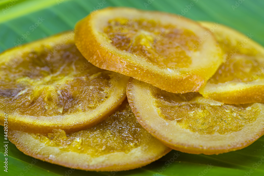 Preserved sliced dried oranges on a green banana leaf close up macro citrus fruit omn natural green background Preserved sliced dried oranges on a green banana leaf close up macro citrus fruit omn natural green background