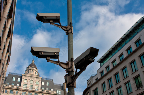CCTV cameras in central London UK with buildings in the background with blue sky and some clouds with copy space