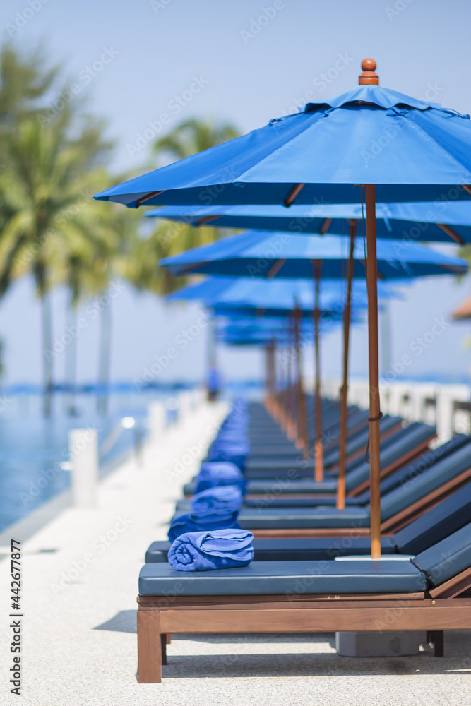 Blue Sun Umbrellas and Deck Chairs by a Swimming Pool
