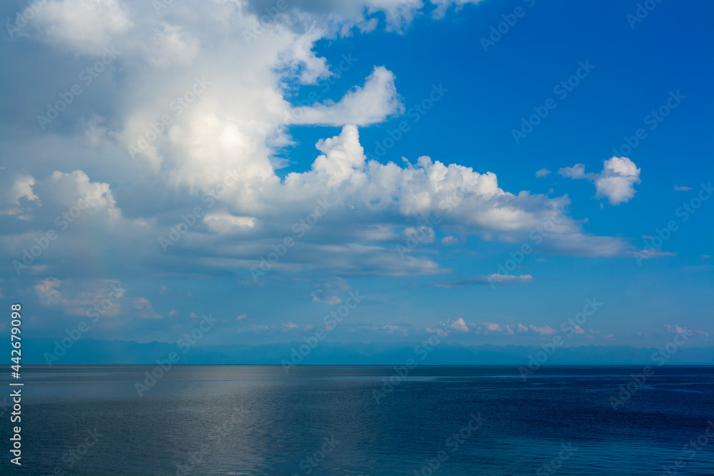 Cumulus clouds against the blue sky over Lake Baikal. Horizontal image.