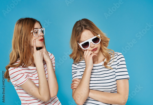 two cheerful girlfriends with glasses summer fashion friendship blue background © SHOTPRIME STUDIO