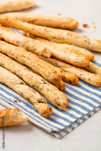 Homemade breadsticks with herbs on a gray concrete background. Grissini - Italian breadsticks