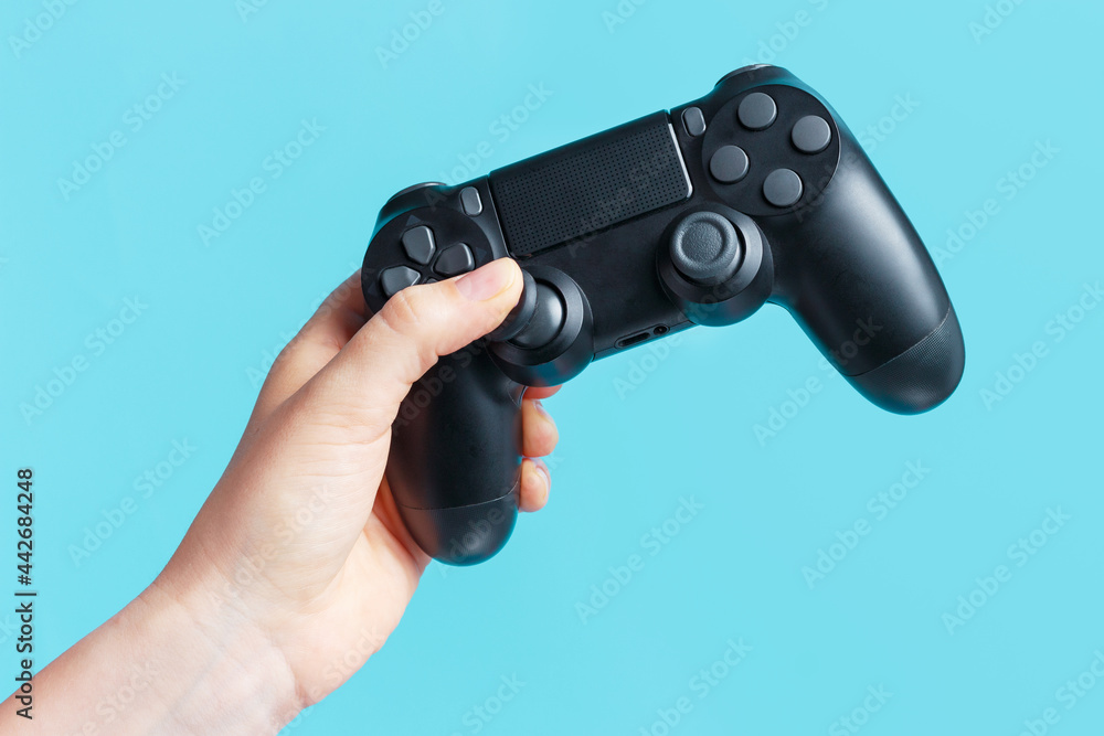Female hand holding video game joystick on blue background. Female hand holding video game joystick on blue background.