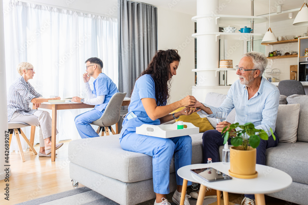 Obraz premium Female nurse talking to senior patient while being in a home visit.