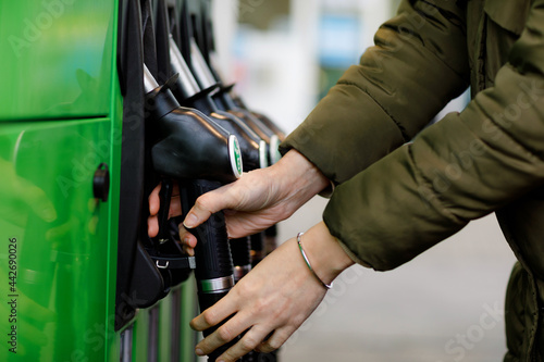 Close-up of hands of woman at self-service gas station, hold fuel nozzle and refuel the car with petrol, diesel, gas. Close up of filling auto with gasoline or benzine. Self service gas pump © Irina Schmidt