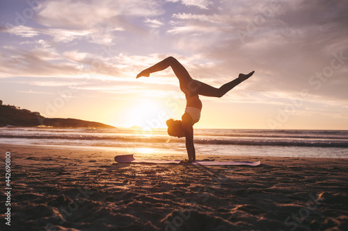 Woman doing yoga pose handstand on beach photo