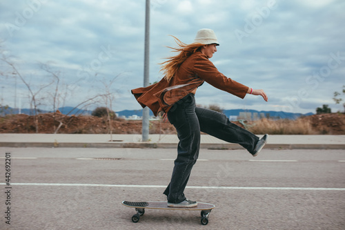 Active young lady riding skateboard in countryside photo