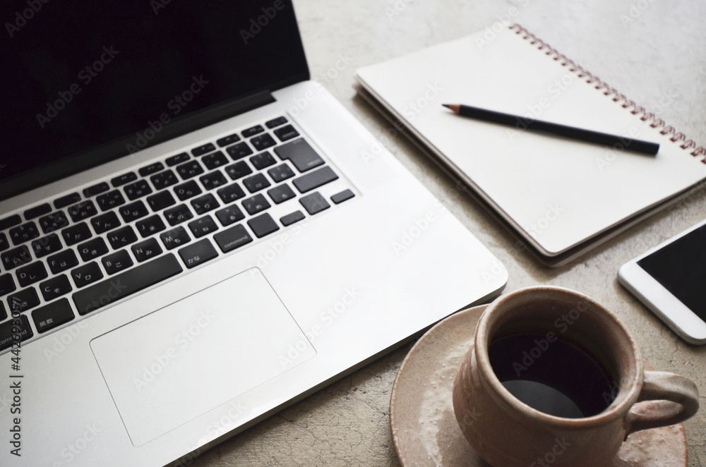Concrete table with a laptop, smartphone, notebook, pencil and a cup of coffee. Concrete table with a laptop, smartphone, notebook, pencil and a cup of coffee.