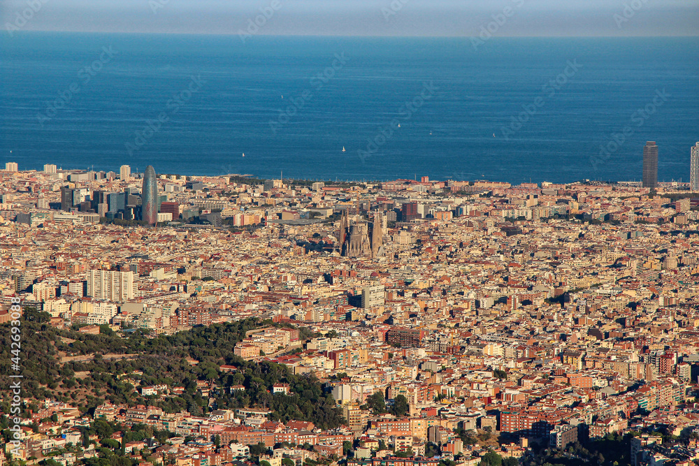 Top view of Barcelona Spain, yellow houses with red roofs, cathedrals, blue sky and blue sea with yachts. Soft focus