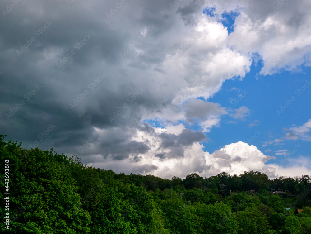 Massive dark storm clouds coming from right over a wooded hill Massive dark storm clouds coming from right over a wooded hill