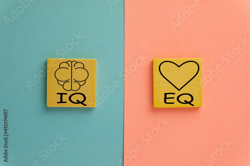 IQ and EQ on wooden cube over pink and blue pastel background use for emotional and intelligence quotient ,Opposites concept.,