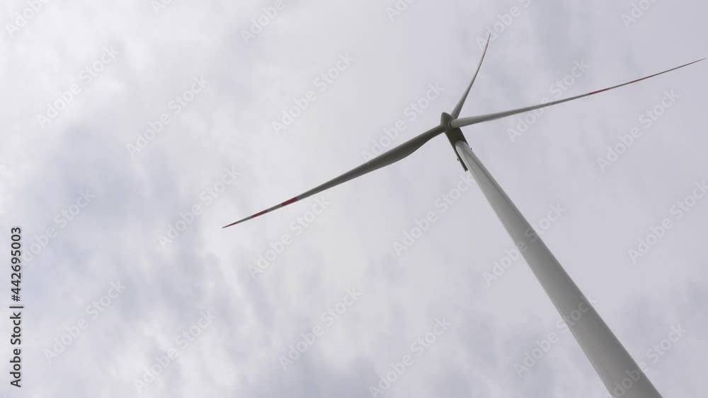 A wind turbine rotor slowly rotates in a light wind. Handheld shot. Naturally soft light on a cloudy day