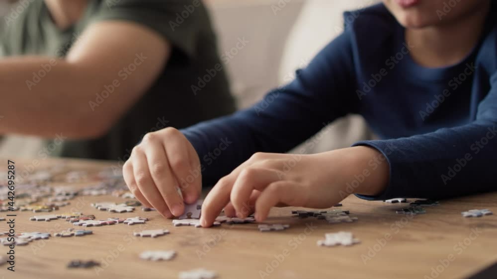 Close up video of father and son solving jigsaw puzzle. Shot with RED helium camera in 8K. Close up video of father and son solving jigsaw puzzle. Shot with RED helium camera in 8K.