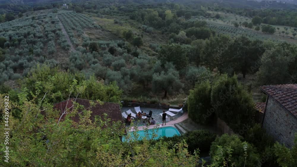 Drone slowly flying away from a small pool with people on vacation, showing stunning nature landscape behind it in Florence. Drone slowly flying away from a small pool with people on vacation, showing stunning nature landscape behind it in Florence.