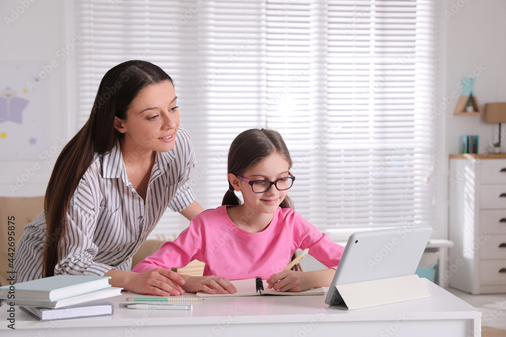 Mother helping her daughter doing homework with tablet at home Mother helping her daughter doing homework with tablet at home
