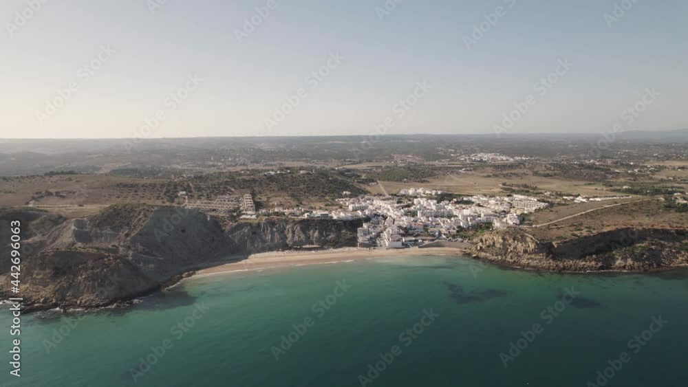 Cinematic aerial view turquoise sea and old fishing village with whitewashed cottages houses in Burgau Portugal. Cinematic aerial view turquoise sea and old fishing village with whitewashed cottages houses in Burgau Portugal.