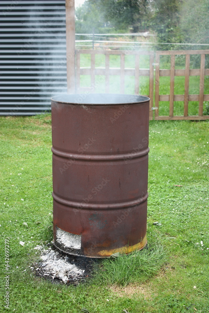 Qualmende Feuertonne auf einer Wiese Qualmende Feuertonne auf einer Wiese