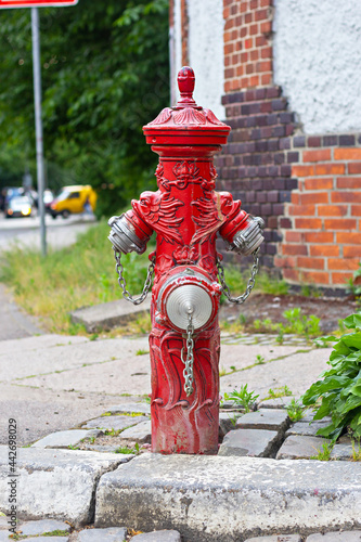 Old red German fire hydrant on the 1812 Goda street in Kaliningrad, Russia..The fire hydrant is decorated with the heads of dragon monsters.