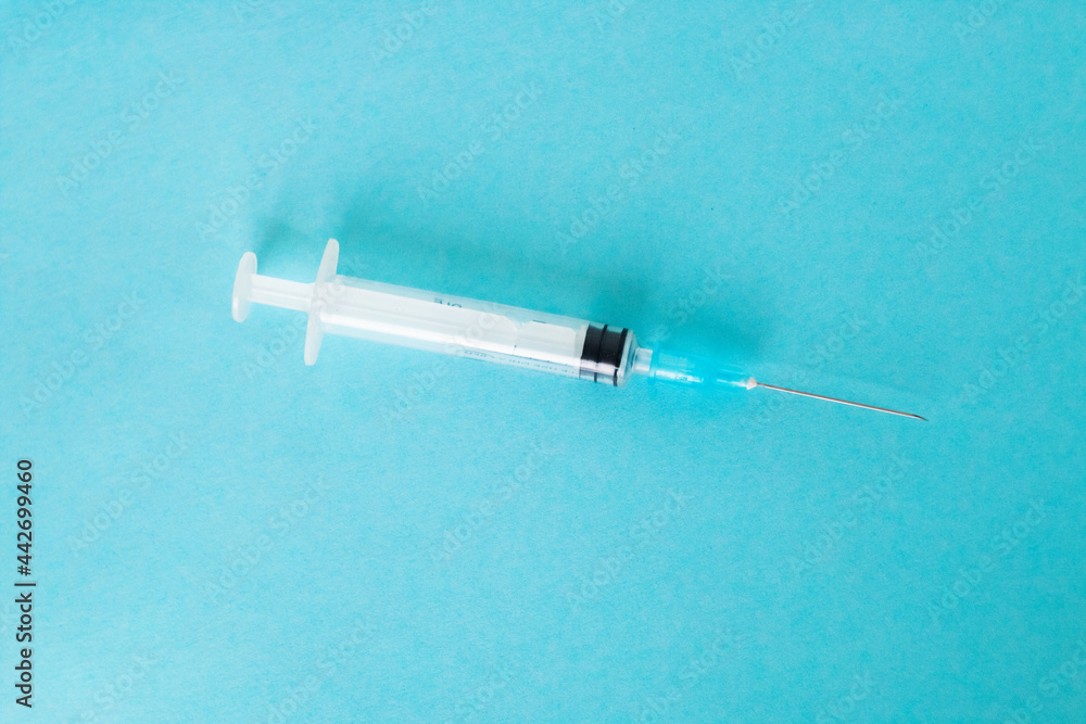 Syringe isolated on a blue background. Syringe close-up. A shot in a syringe. Syringe isolated on a blue background. Syringe close-up. A shot in a syringe.