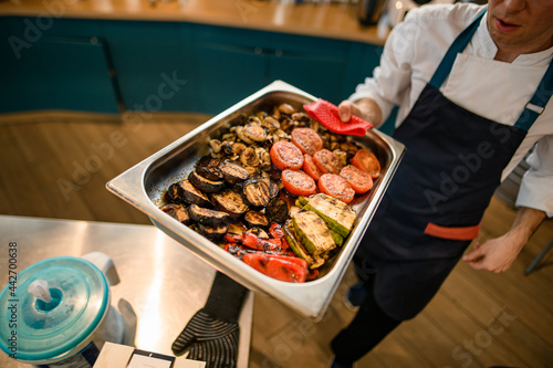 Valokuva baking sheet with various healthy baked vegetables in hand of chef