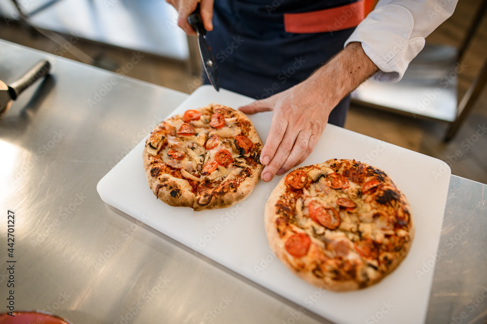 top view on pizzas on cutting board that chef cutted into pieces with cutter