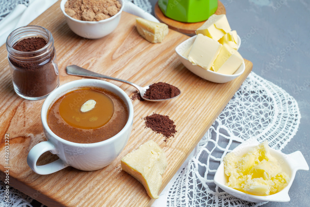 KETOGENIC KETO DIET DRINK. Coffee and cocoa mixed with ghee. Cup of bulletproof coffee with cocoa and ingredients on wooden background KETOGENIC KETO DIET DRINK. Coffee and cocoa mixed with ghee. Cup of bulletproof coffee with cocoa and ingredients on wooden background