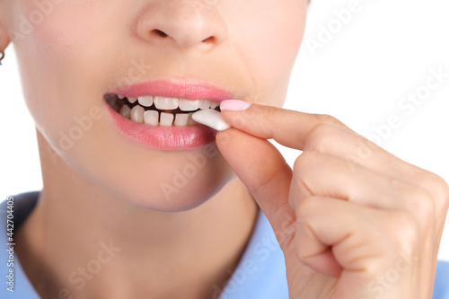 Young woman puts white chewing gum in mouth closeup