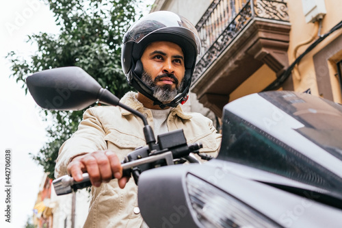 Hispanic motorcyclist driving modern bike on city street