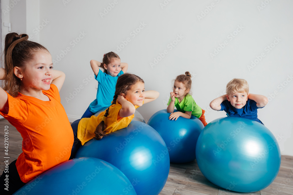 © oksix - Kids doing physical exercises on large fitballs