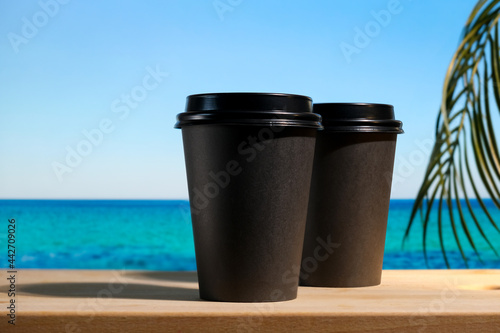 Two takeaway coffee or tea containers on summer tropical background. Coffee shop, beach bar concept. © meteoritka