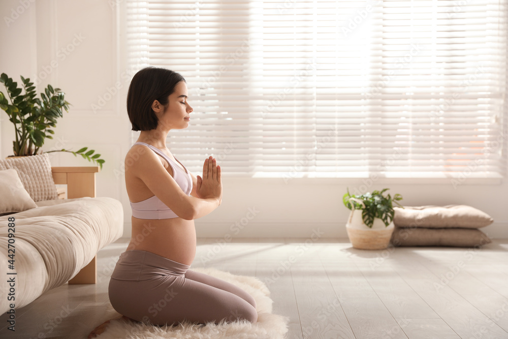 Young pregnant woman practicing yoga at home, space for text Young pregnant woman practicing yoga at home, space for text