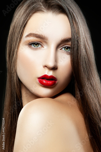 Portrait of a beautiful girl in studio with make-up, red lipstick and healthy skin. Black background