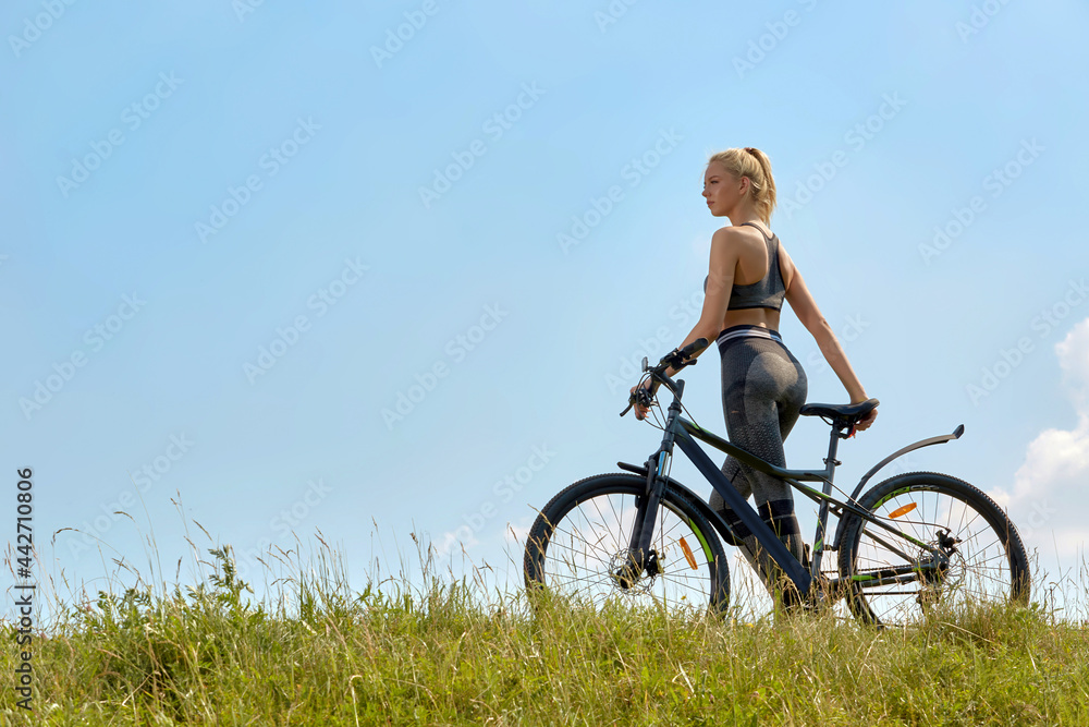 Girl on a bicycle on a background of blue sky and green grass Girl on a bicycle on a background of blue sky and green grass