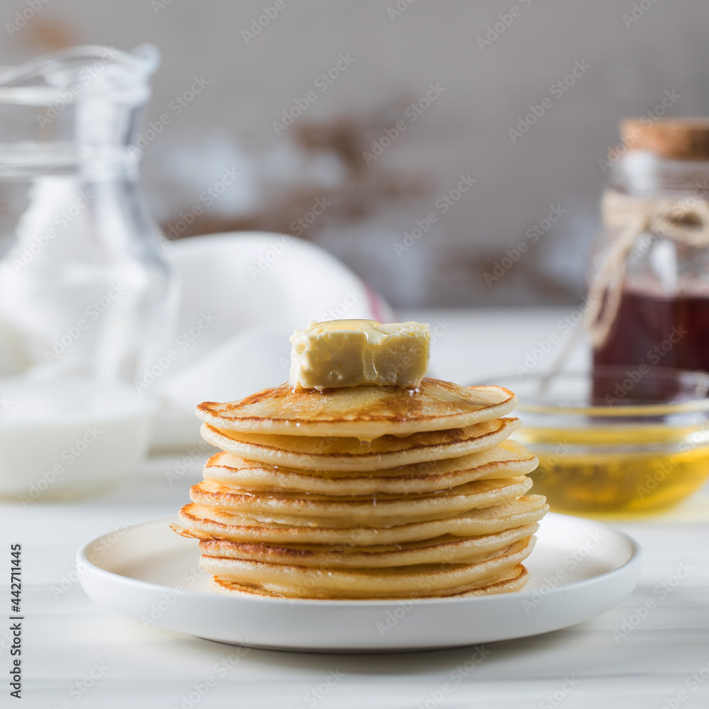 The pancakes are stacked in a plate with a piece of butter and drizzled with honey sauce. Breakfast concept. The pancakes are stacked in a plate with a piece of butter and drizzled with honey sauce. Breakfast concept.