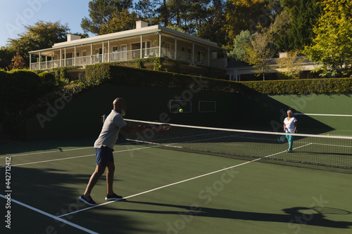 Senior african american couple playing tennis on tennis court